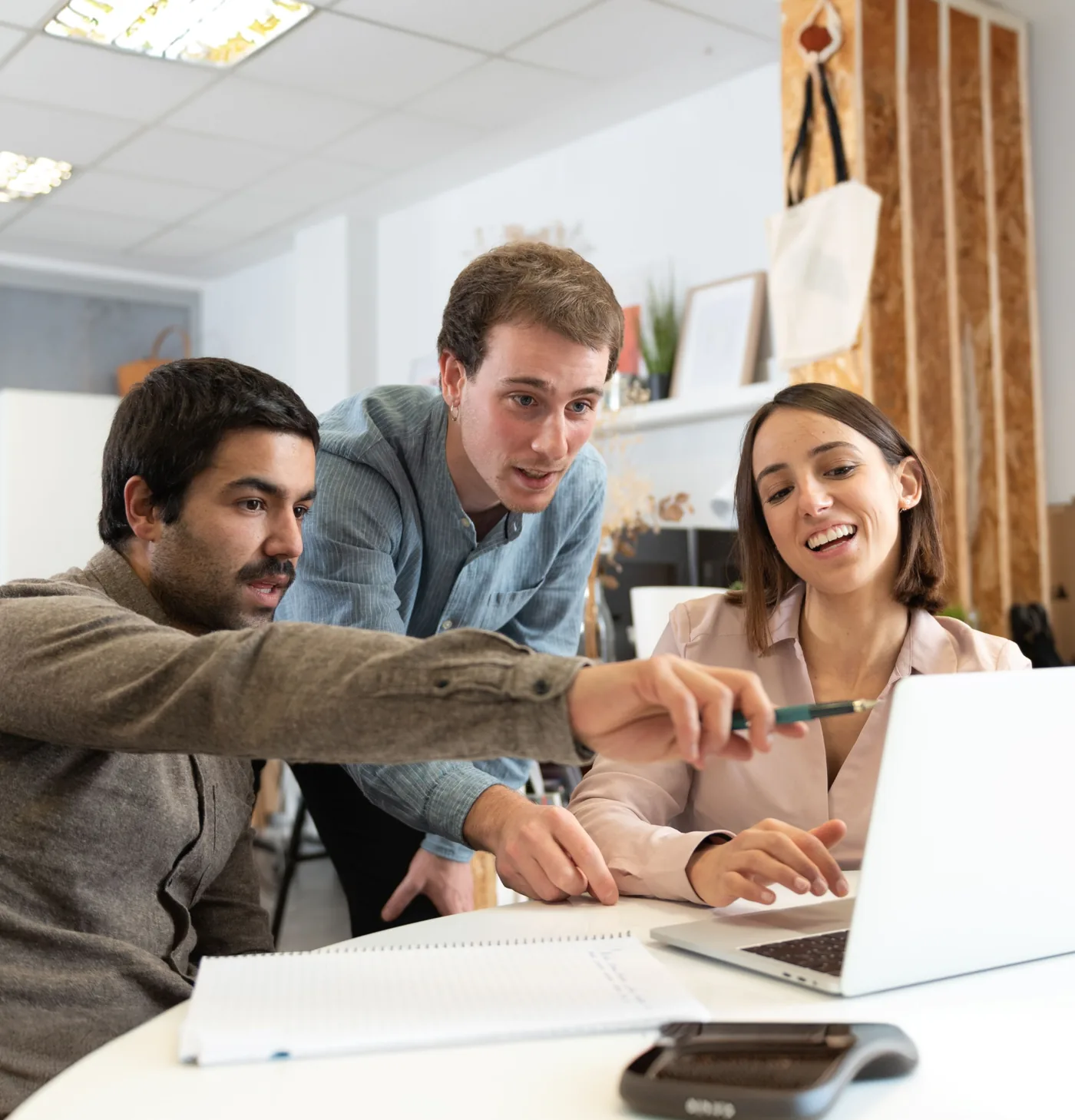 Three colleagues reviewing pricing on a laptop together